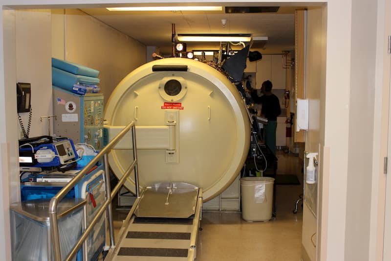 ED member standing next to a hyperbaric chamber